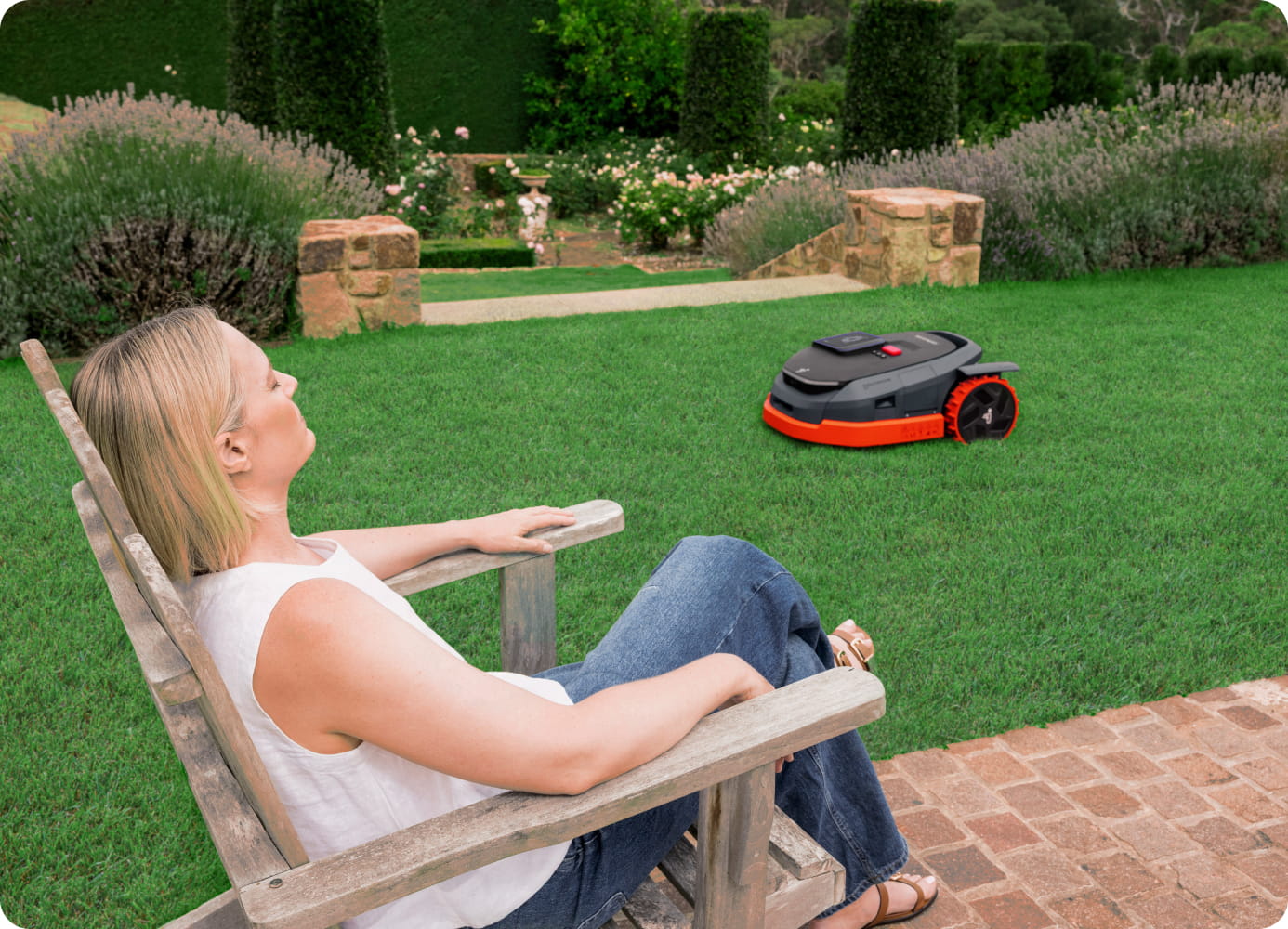 Navimow i110N robot lawn mower mows grass while woman rests.