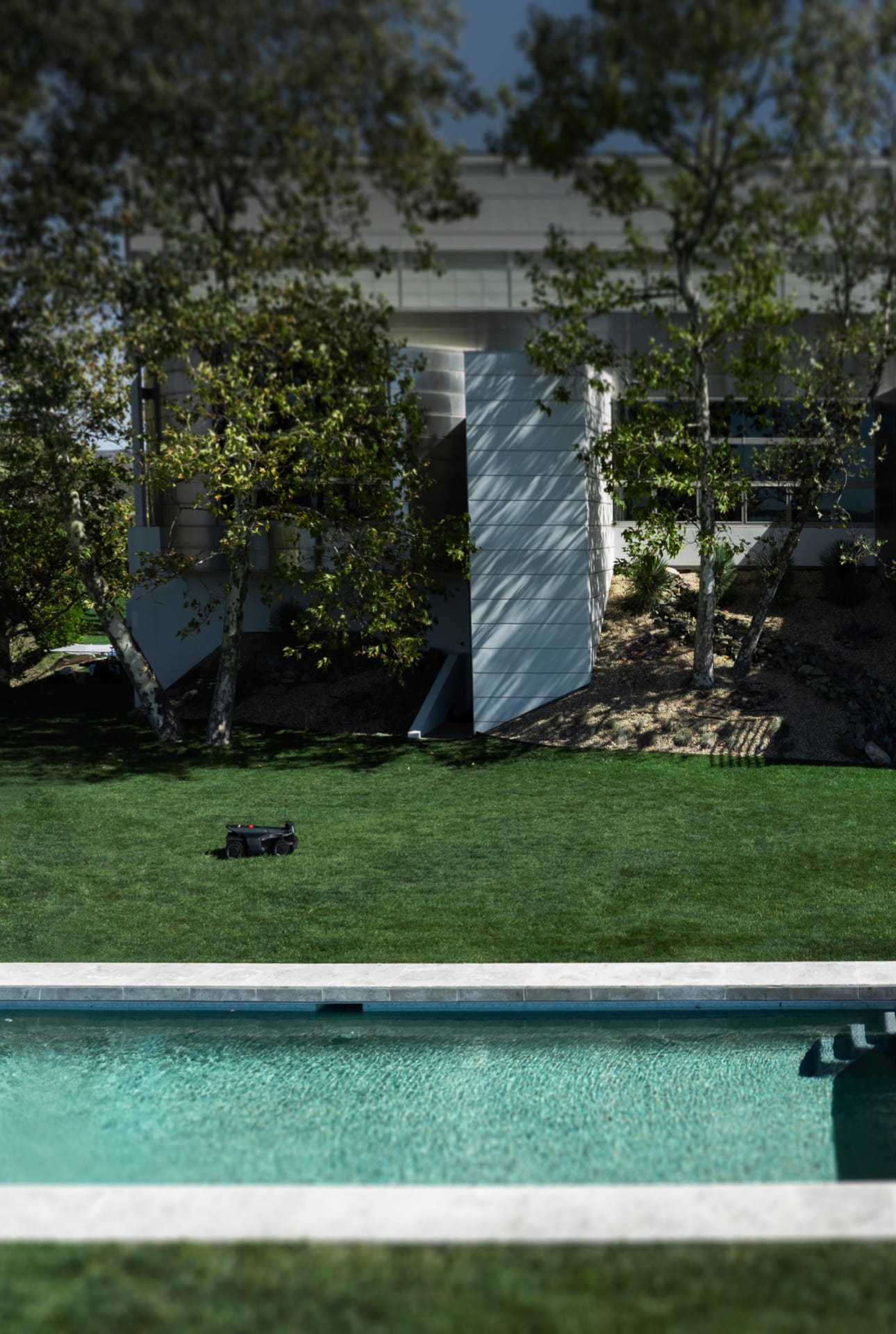 Navimow i110N robot lawn mower mows grass near a pool.