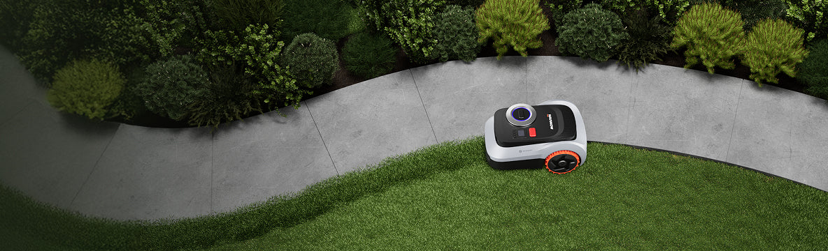 Navimow i110N robot lawn mower on a curved stone path.